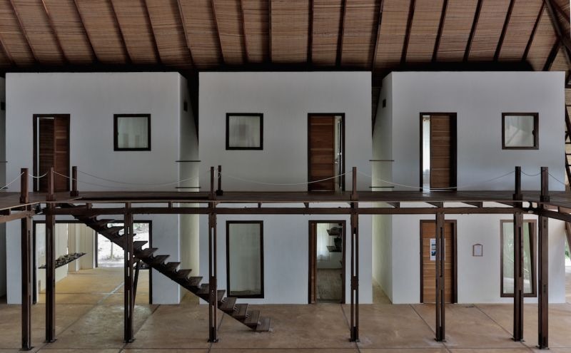 A two-storey white accommodation block with timber doors, an external staircase up the middle