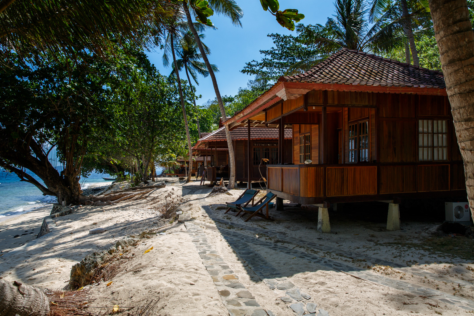 Cottages raised on posts along the shoreline, the sea running blue past the last of them.