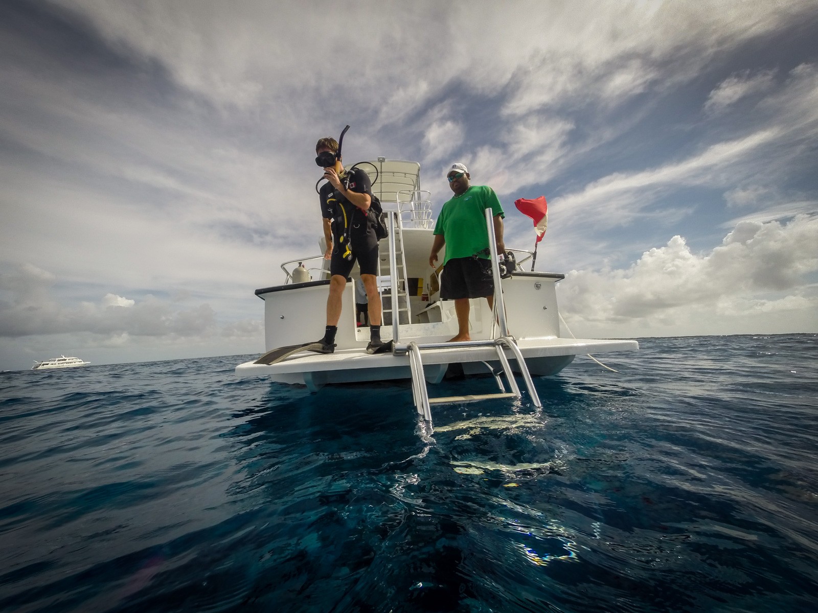 Two men on the poling platform of a flats skiff, standing against a big cloudy sky