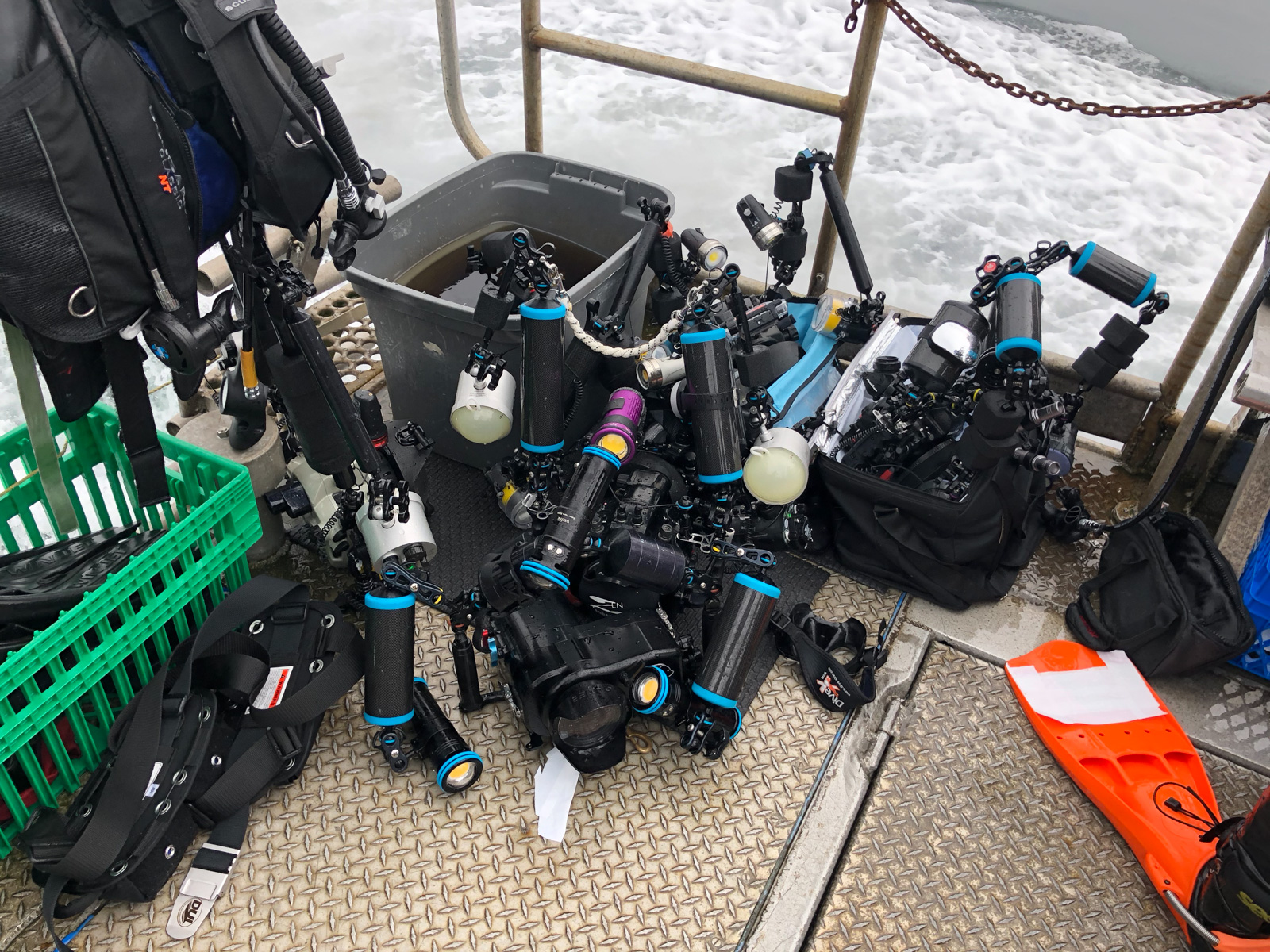 Housed cameras and strobe arms crowded onto the boat's camera table with the wake running past astern.