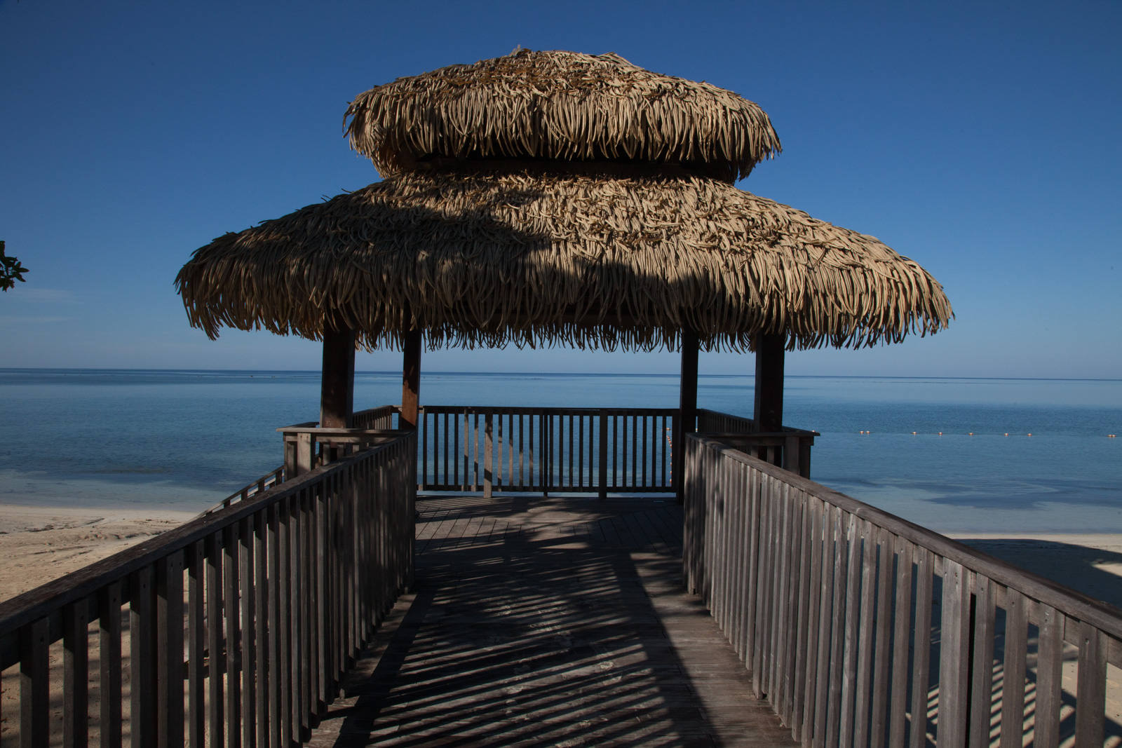 A boardwalk running out to two thatched palapas over the shallows.