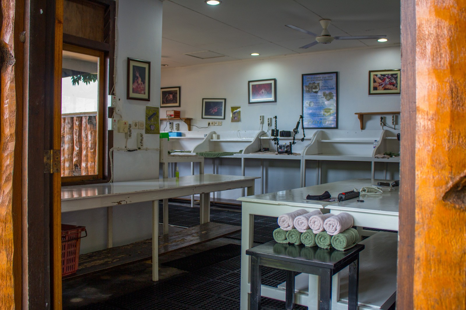 A camera room with white benches down both sides, framed prints on the wall and towels rolled ready at each station