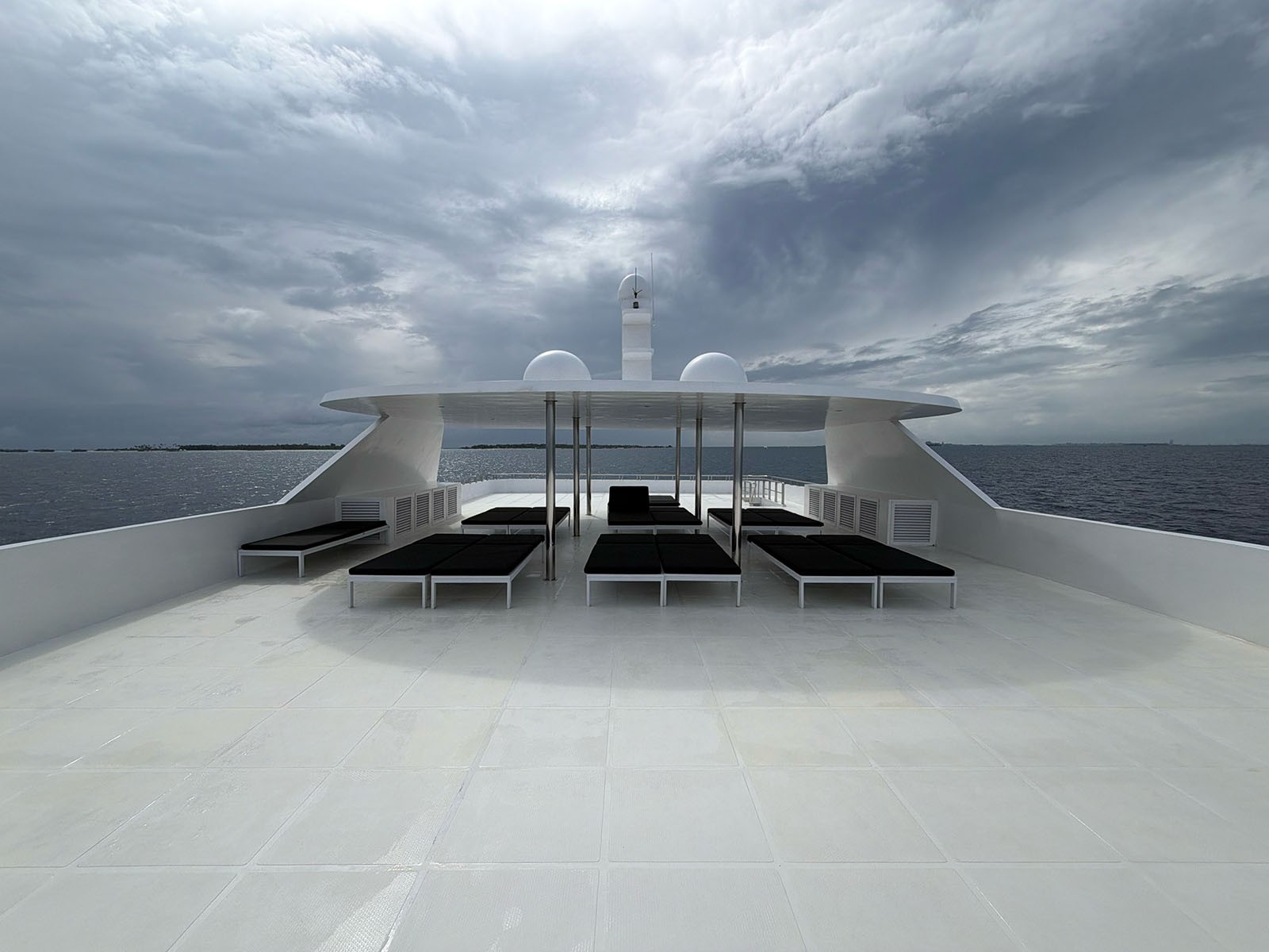 The empty upper sun deck of a liveaboard under flat grey cloud, loungers folded flat