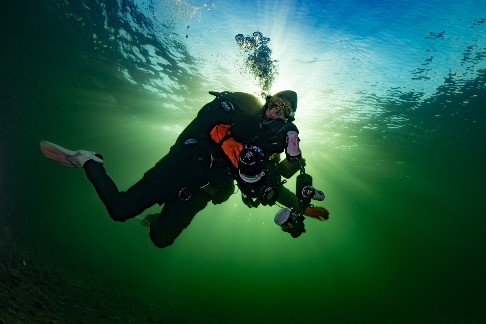 Drysuited diver with camera, backlit green, Howe Sound