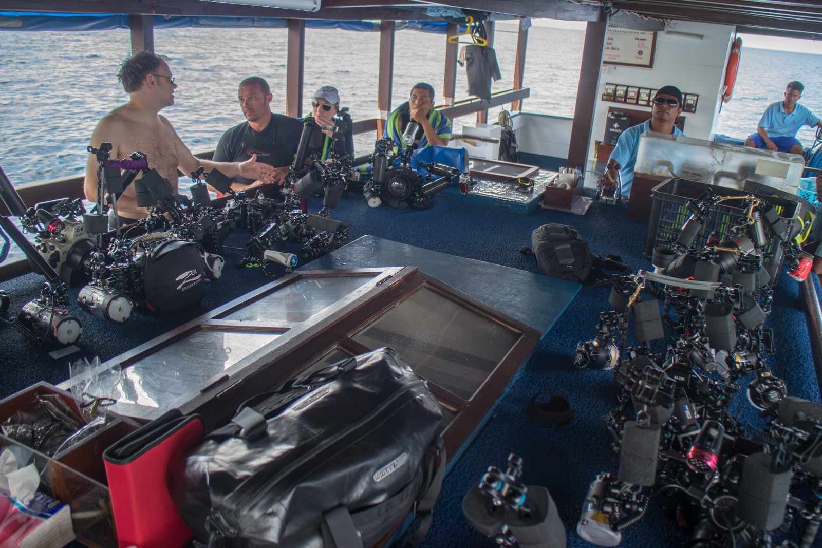 A camera room with divers working at benches, housings and strobes laid out along the counter